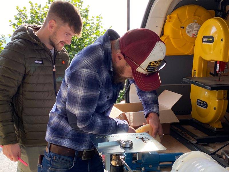 a farrier practices welding plastic horseshoes while another farrier observes