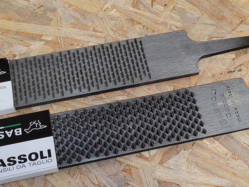Le modèle Bassoli Doppia repose sur une planche en bois ; ses deux faces sont visibles, le côté râpe et le côté lime.