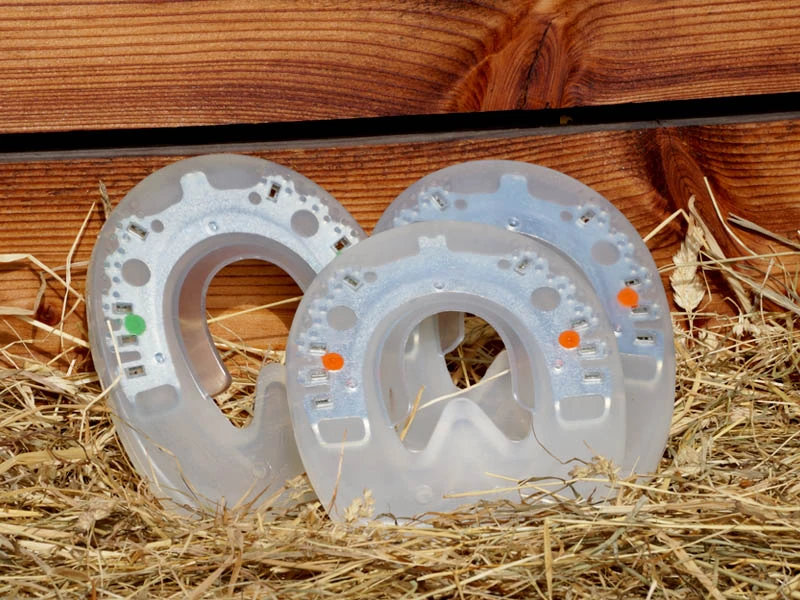 Verschiedene Varianten des Duplo Nailless Kunststoffhufeisen zum Kleben: Man sieht die Version mit grünem und orangem Punkt. Die Punkte geben den Härtegrad des Kunststoffs an.