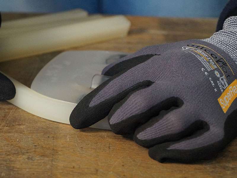 a farrier wears SuperFlex assembly gloves from Allcolor while extending a urethane horseshoe