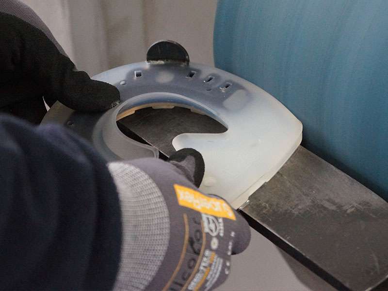 The farrier wears SuperFlex assembly gloves from Allcolor and grinds an alternative horseshoe to fit on a belt grinder