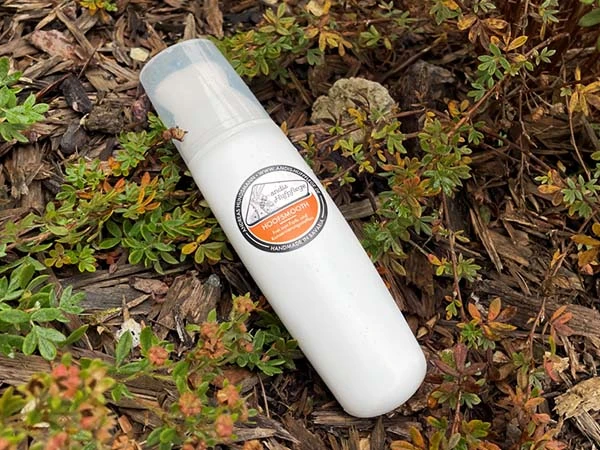 A bottle of Hoofsmooth with brush lies on a twig-covered surface.