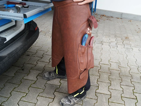 Un maniscalco indossa il grembiule Elite lungo in pelle marrone.
