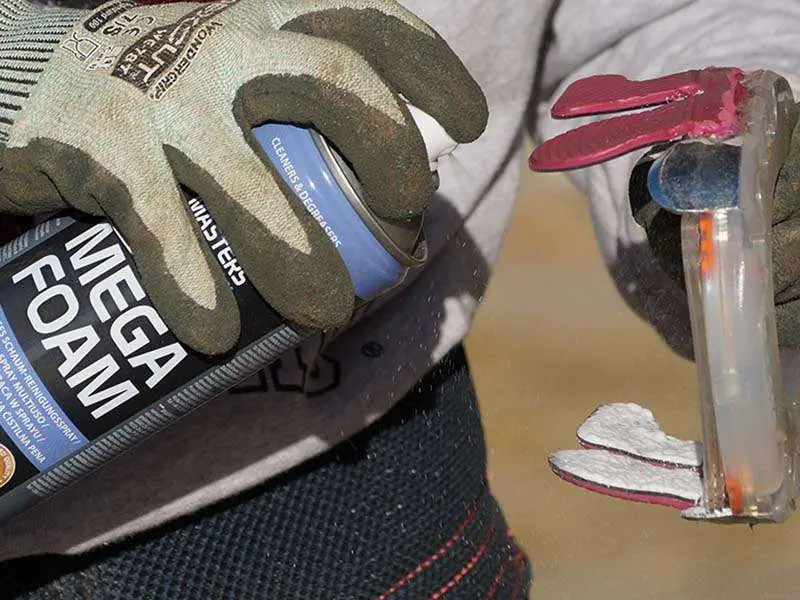 Farrier sprays an adhesive horseshoe with MEGA FOAM foam cleaner for degreasing