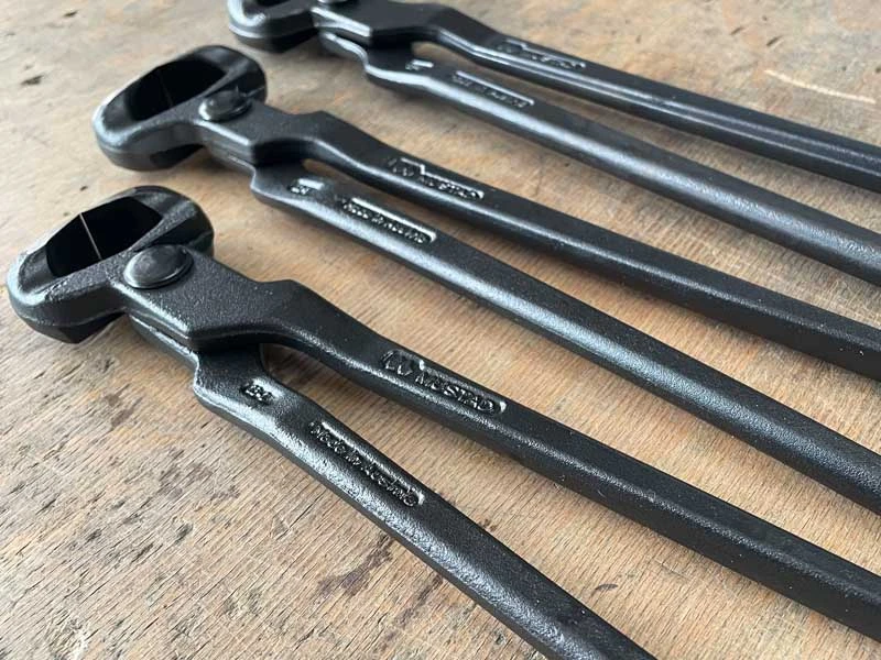 Die 3 Modelle der Huschneidezange von Mustad liegen auf einer Werkbank.