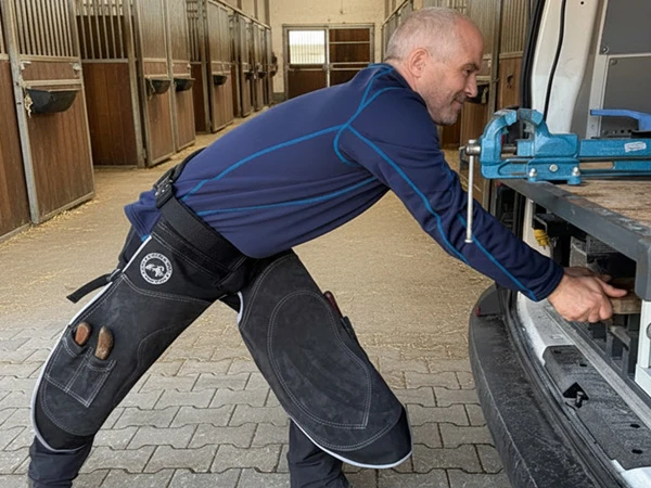 Un maniscalco prepara il suo veicolo da ferratura per un intervento mobile. Indossa un grembiule da maniscalco Hybrid Pro Chaps di Silverback.