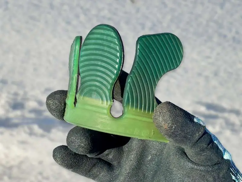 Photo en gros plan d’une manchette collante souple, de couleur verte, pour fer collé en hiver. De la neige en arrière-plan.