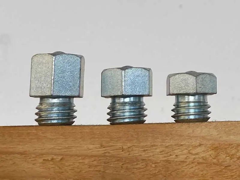 Tre ramponi esagonali di altezze diverse sono posizionati su uno scaffale in legno.
