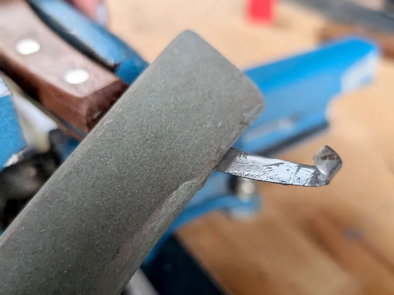 Un maréchal-ferrant affûte une rénette avec une pierre à affûter en carbure de silicium.